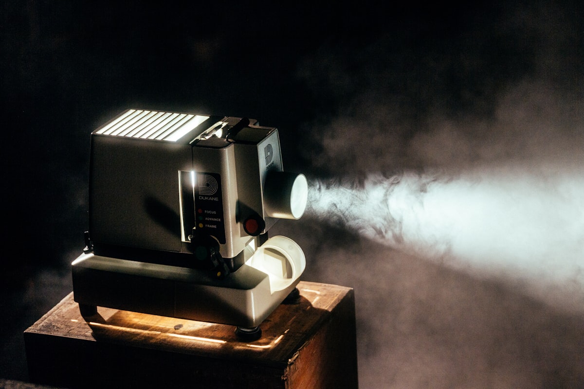 Home cinema setup with mini projector casting image onto white wall in dark room